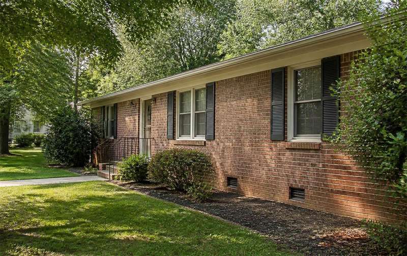 Brick ranch home in a wooded neighborhood with foundation vents visible along the base of the wall